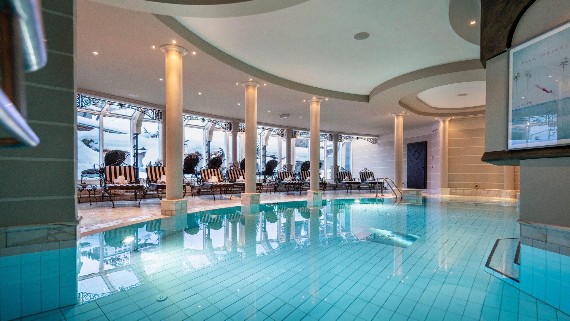 Indoor pool with stylish loungers and large windows for natural light.