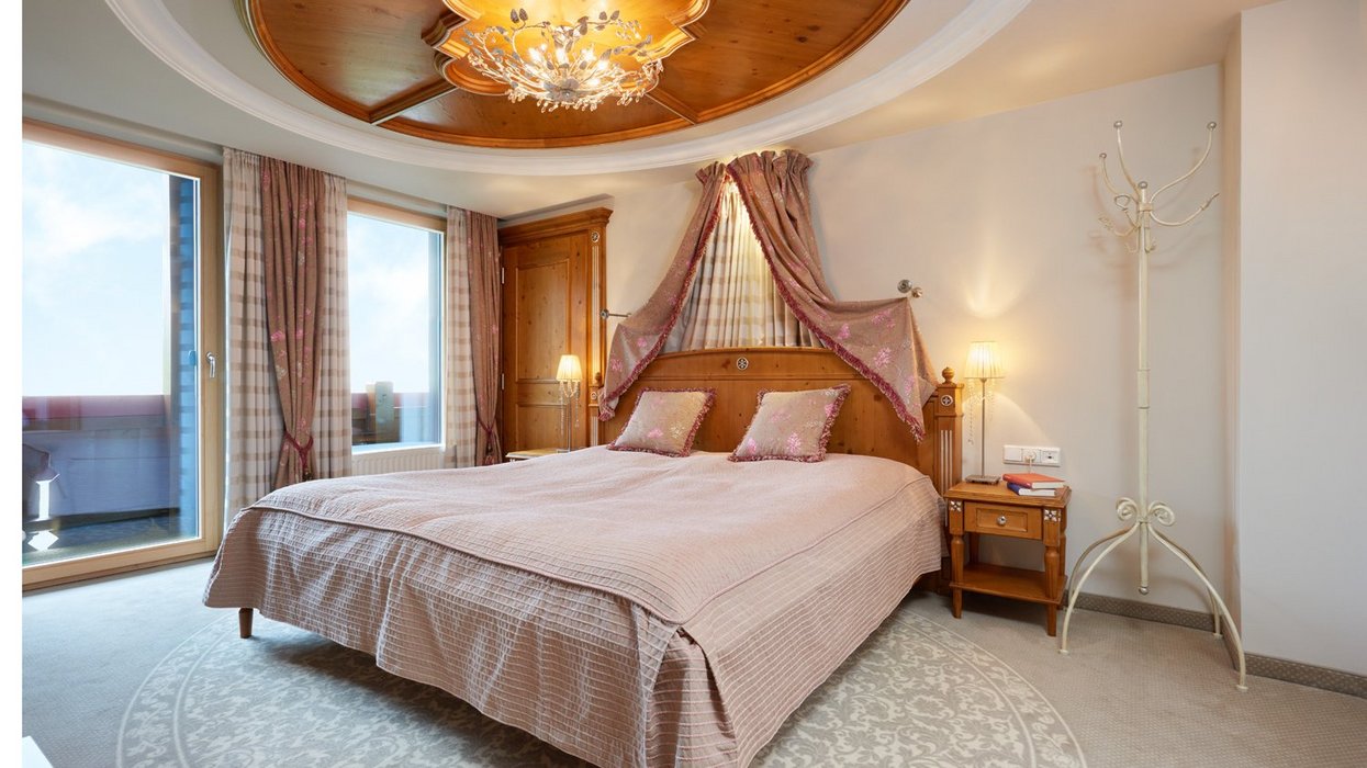 Elegant room with four-poster bed, wooden ceiling and decorative curtains.