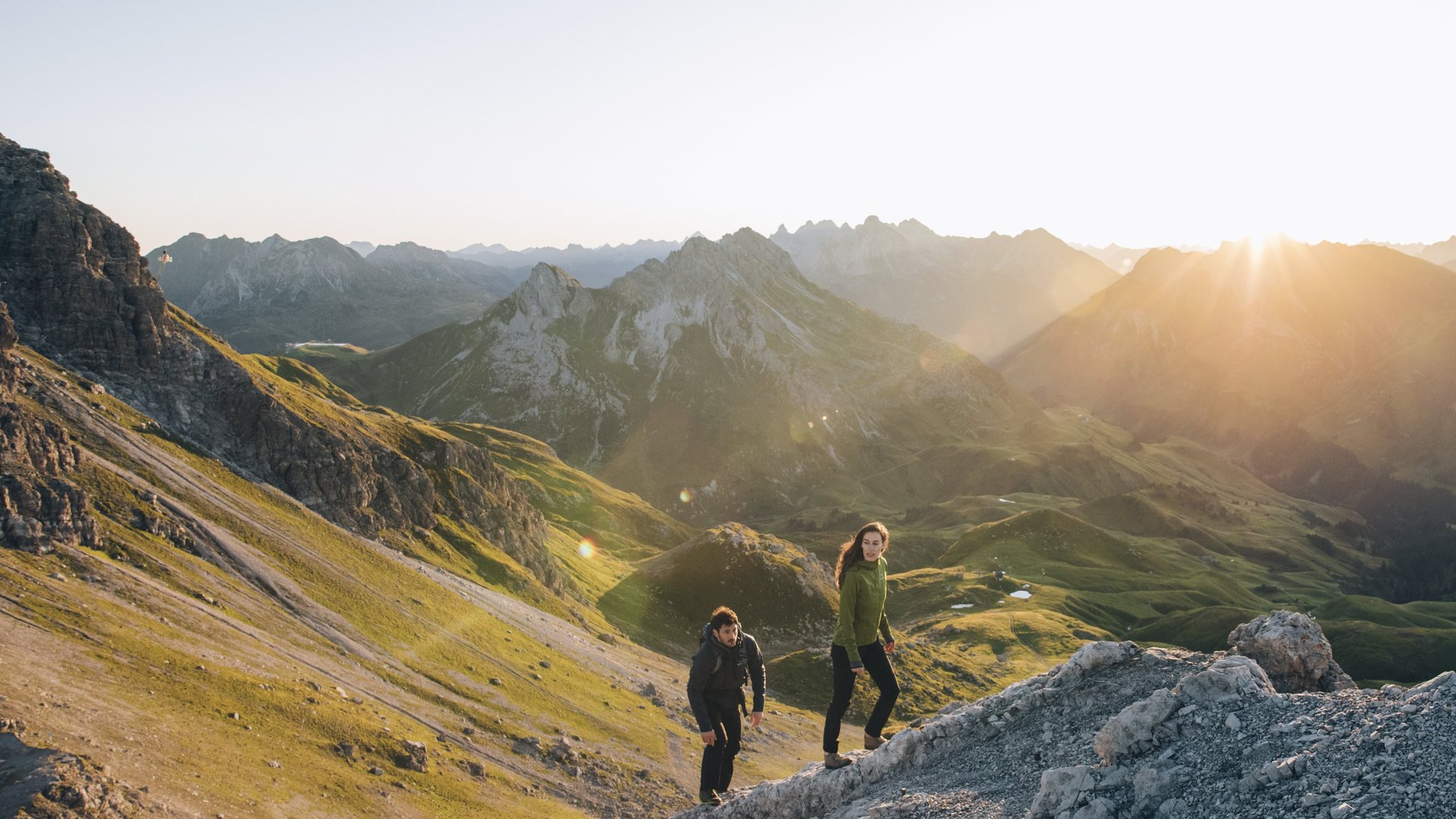 Two people hiking at sunrise in the picturesque Arlberg mountains.