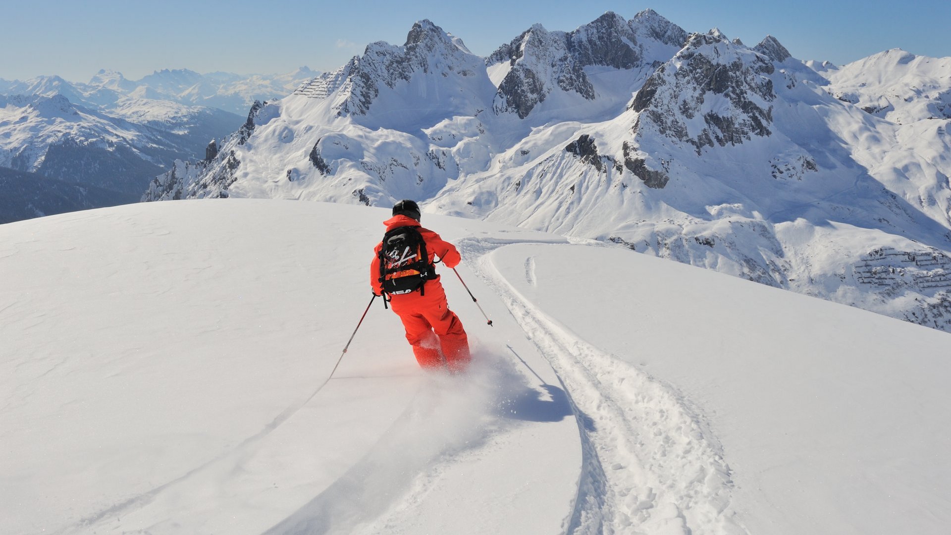 Skier in red clothing enjoys a fantastic descent in the powder snow of the Alps.