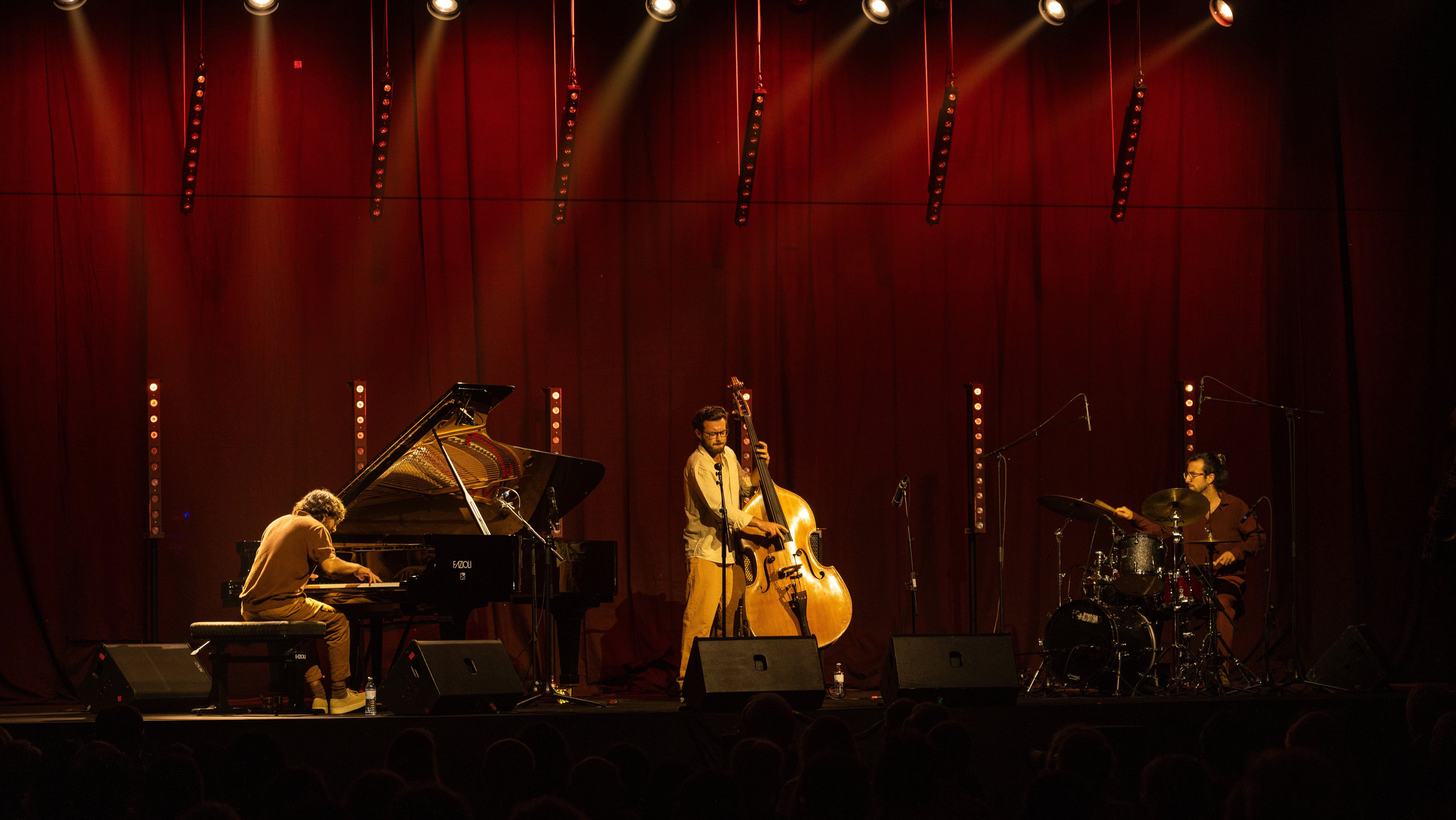 Stimmungsvolles Jazzkonzert Jazztrio spielt auf Bühne mit rotem Vorhang und stimmungsvoller Beleuchtung.