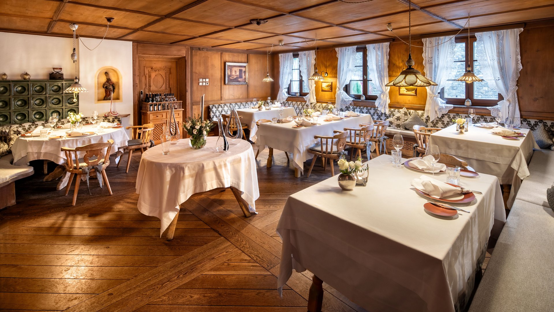 Elegantes Interieur im Romantik Hotel “Die Krone von Lech” Gemütlicher Speisesaal mit holzverkleideten Wänden und schön gedeckten Tischen für Gäste