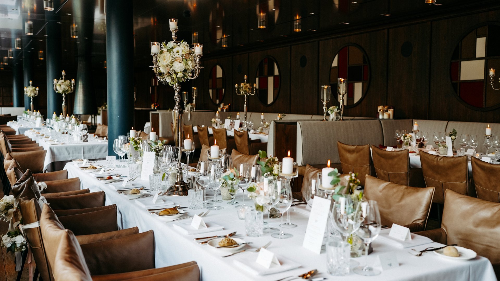 Geschmackvoll gedeckte Tische mit Kerzenlicht und eleganten Blumenarrangements im festlichen Raum.