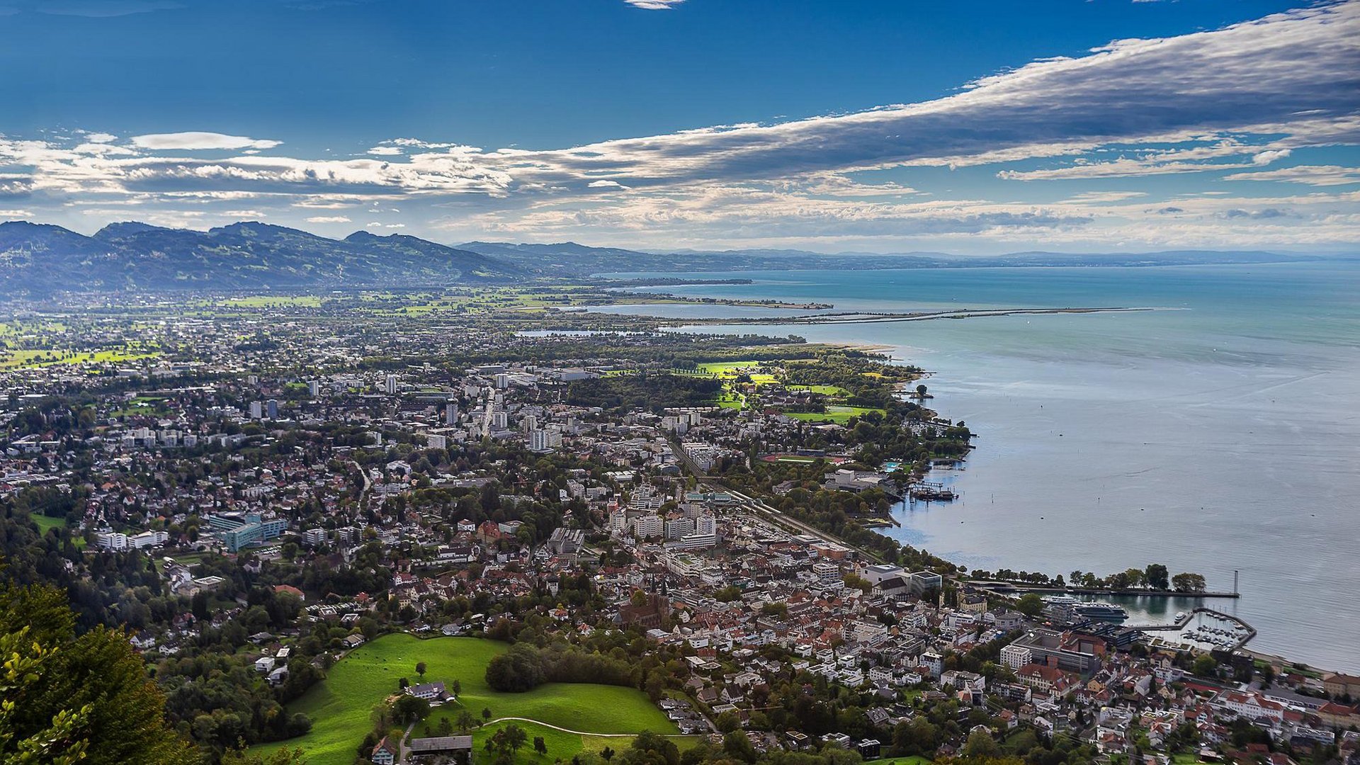 View of Bregenz and Lake Constance under a blue sky and clouds.