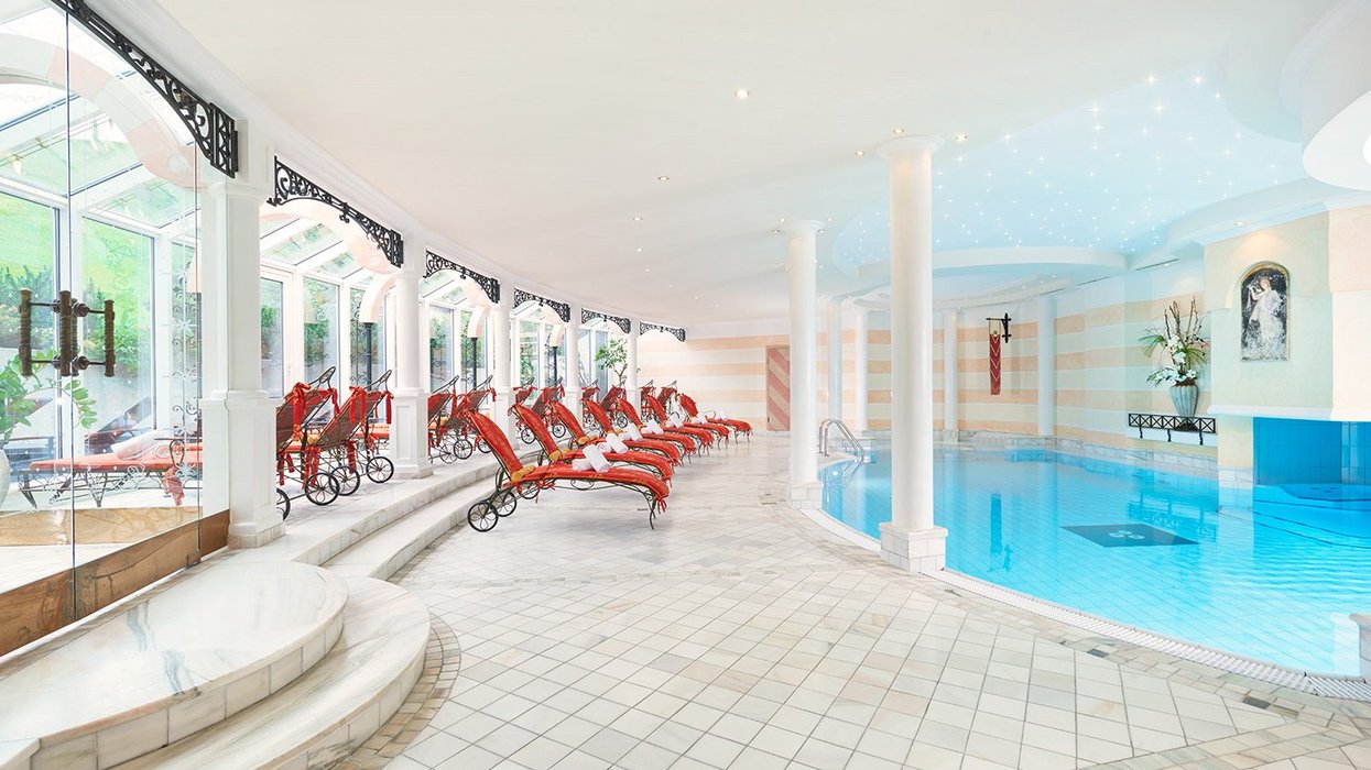 Luxurious pool with red loungers and elegant white pillars