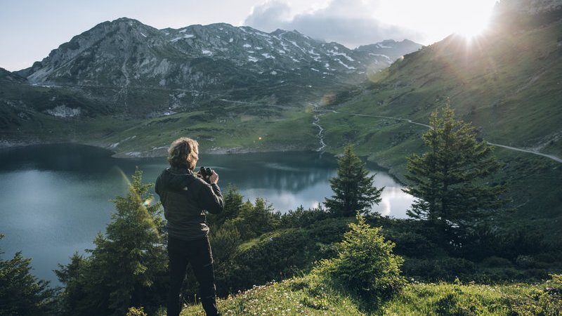 Person overlooking a mountain lake surrounded by alpine scenery.