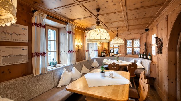 Kuschelbereich mit Holzwänden und großem Tisch in einem Restaurant mit stimmungsvoller Beleuchtung