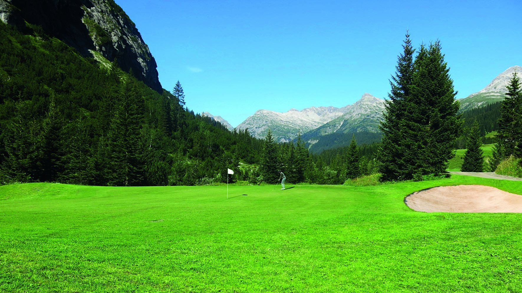 Alpine Golfidylle Grüner Golfplatz umgeben von majestätischen Bergen und duftenden Nadelwäldern.