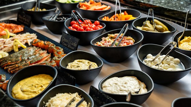 Buffet mit Schüsseln voller Gemüse, Fleisch und Saucen in ansprechender Anordnung