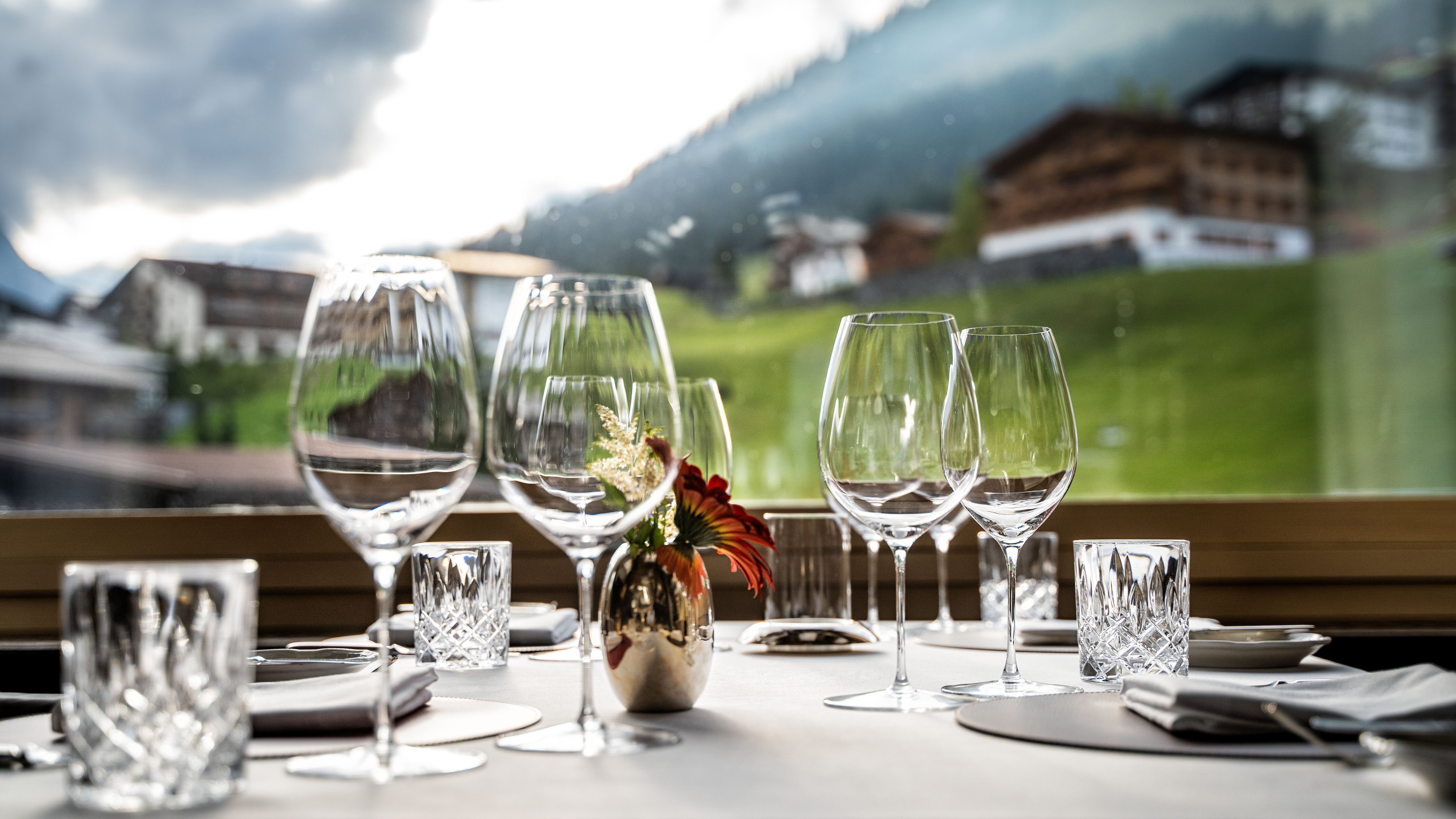 Elegante Tischkultur Fein gedeckter Tisch mit Weingläsern und Blick auf die Berge im Hintergrund.
