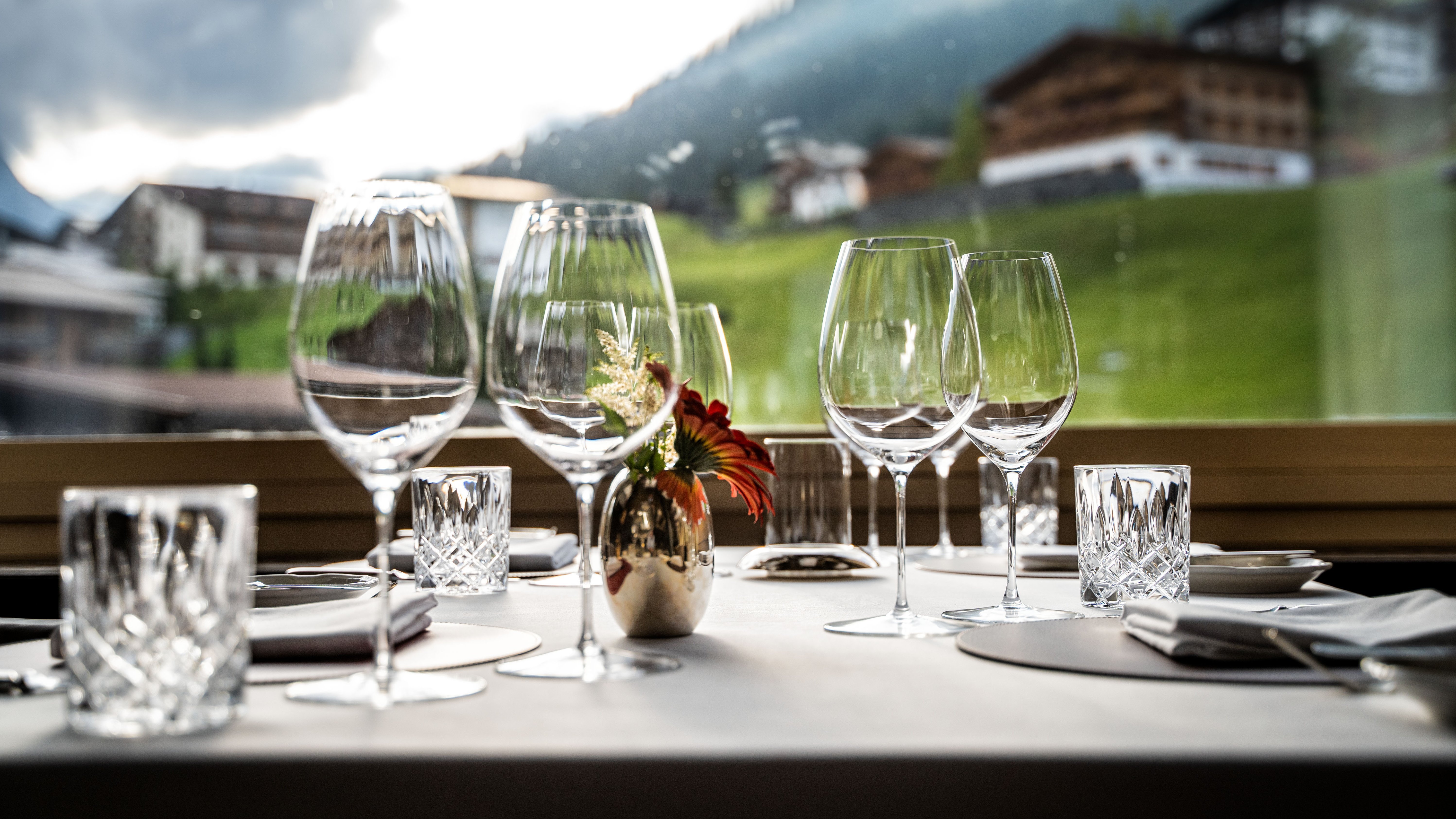 Fein gedeckter Tisch mit Weingläsern und Blick auf die Berge im Hintergrund.